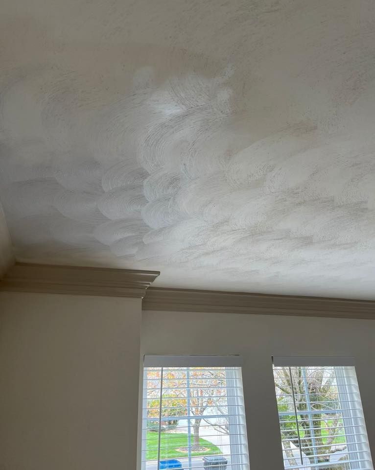 A ceiling in a room with a window and blinds