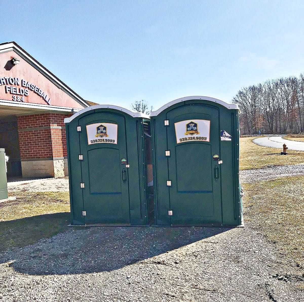 A couple of green portable toilets in front of a building