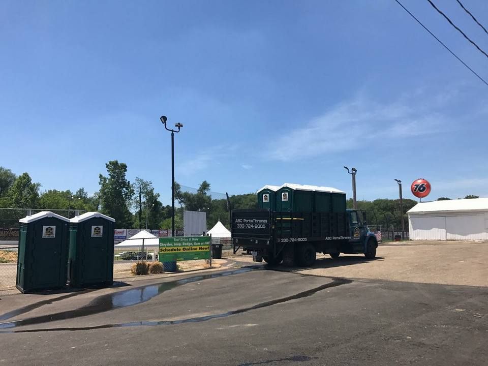 A truck is parked in a parking lot next to portable toilets.
