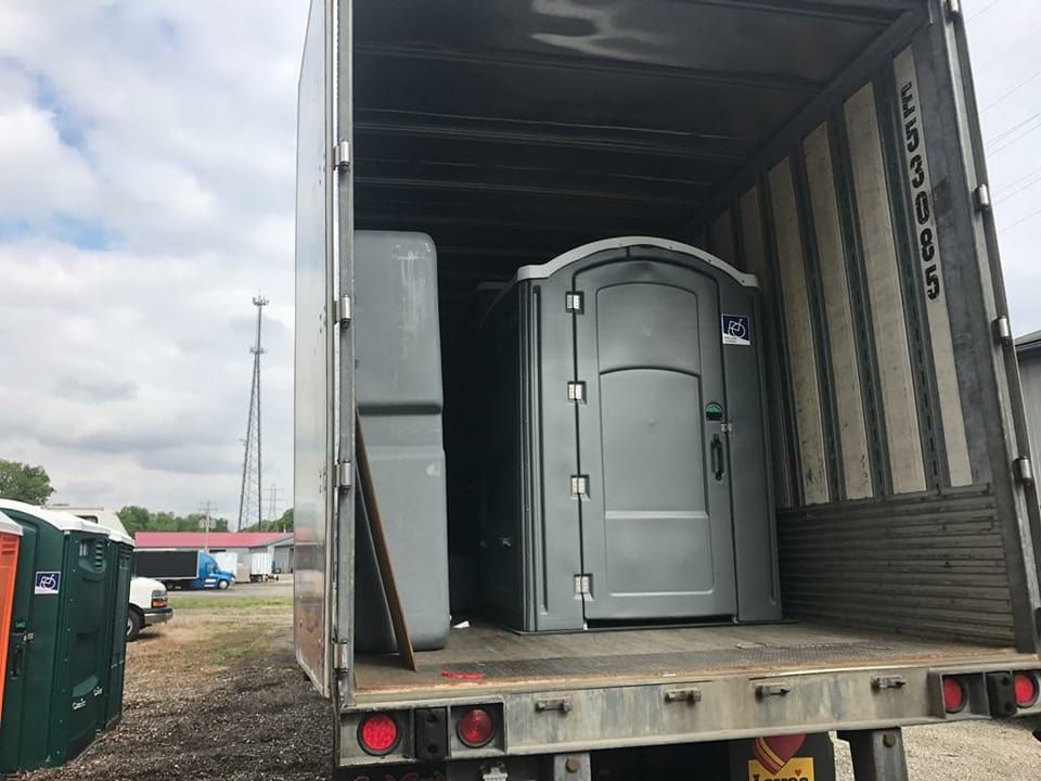 A portable toilet is sitting in the back of a truck.