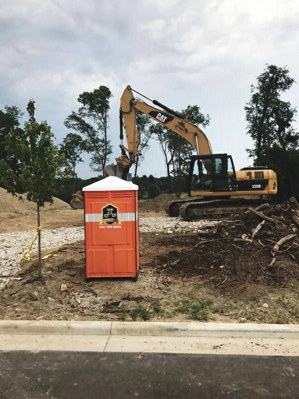 A construction site with a portable toilet and a cat excavator