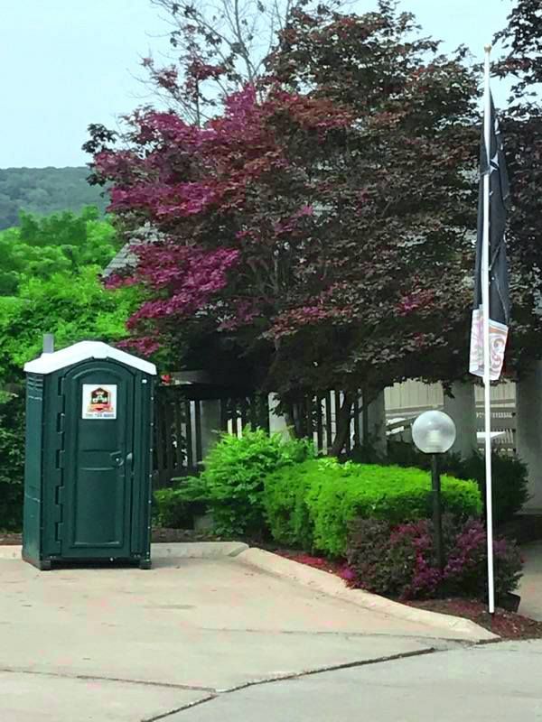 A green portable toilet with a sticker that says ' a ' on it