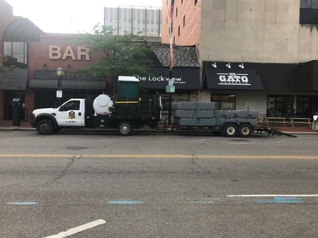 A truck with a trailer is parked on the side of the road in front of a bar.