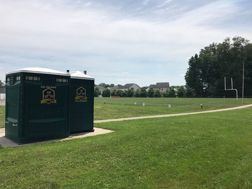 Two portable toilets are sitting in the middle of a grassy field.