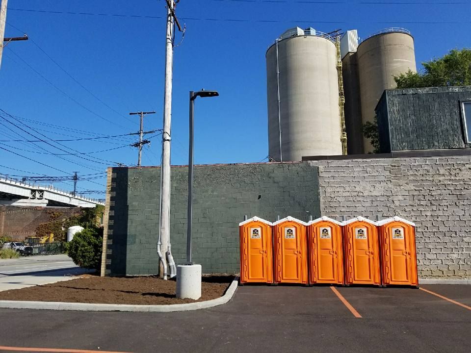 A row of orange portable toilets in a parking lot
