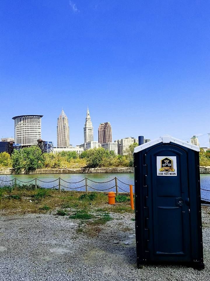 A portable toilet with a city skyline in the background