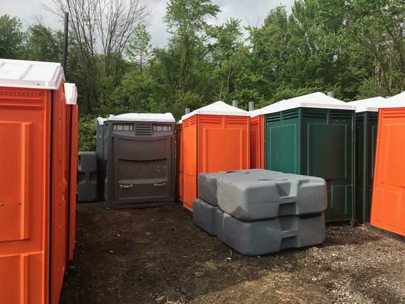 A row of portable toilets are lined up in a field.