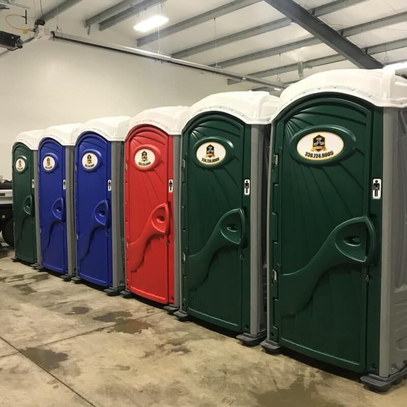 A row of portable toilets are lined up in a warehouse.