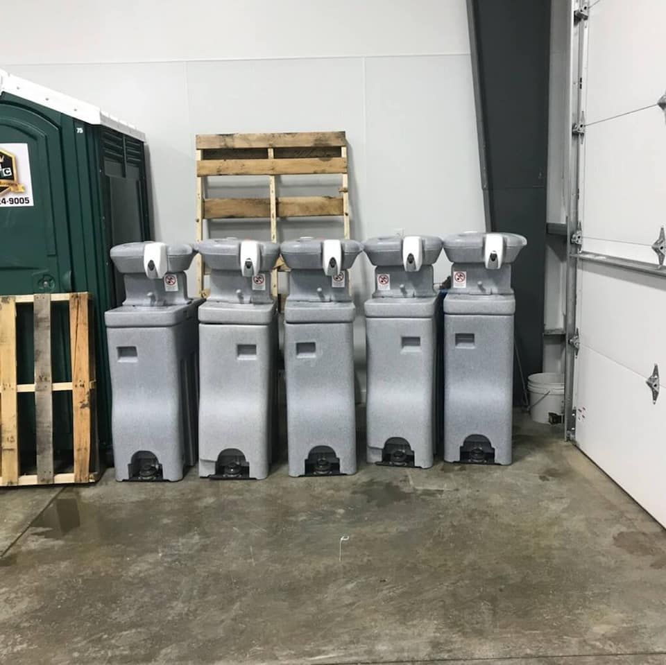 A row of portable sinks are lined up in a garage.