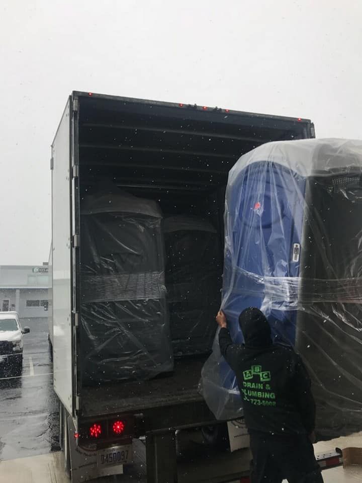 A man is loading a portable toilet into a truck.