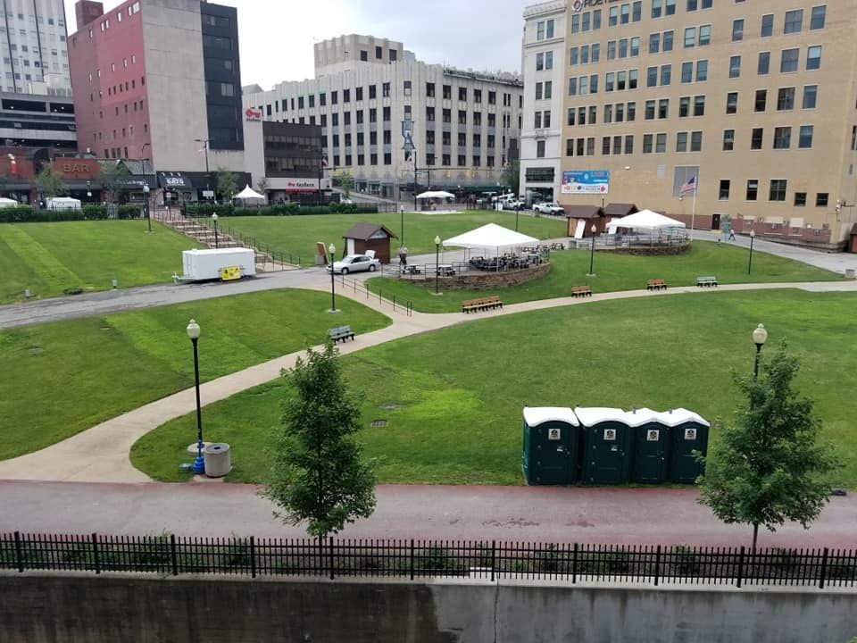 A park with a lot of green portable toilets in it