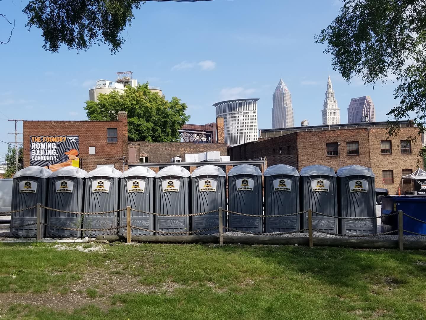 A row of portable toilets are lined up in a grassy field.