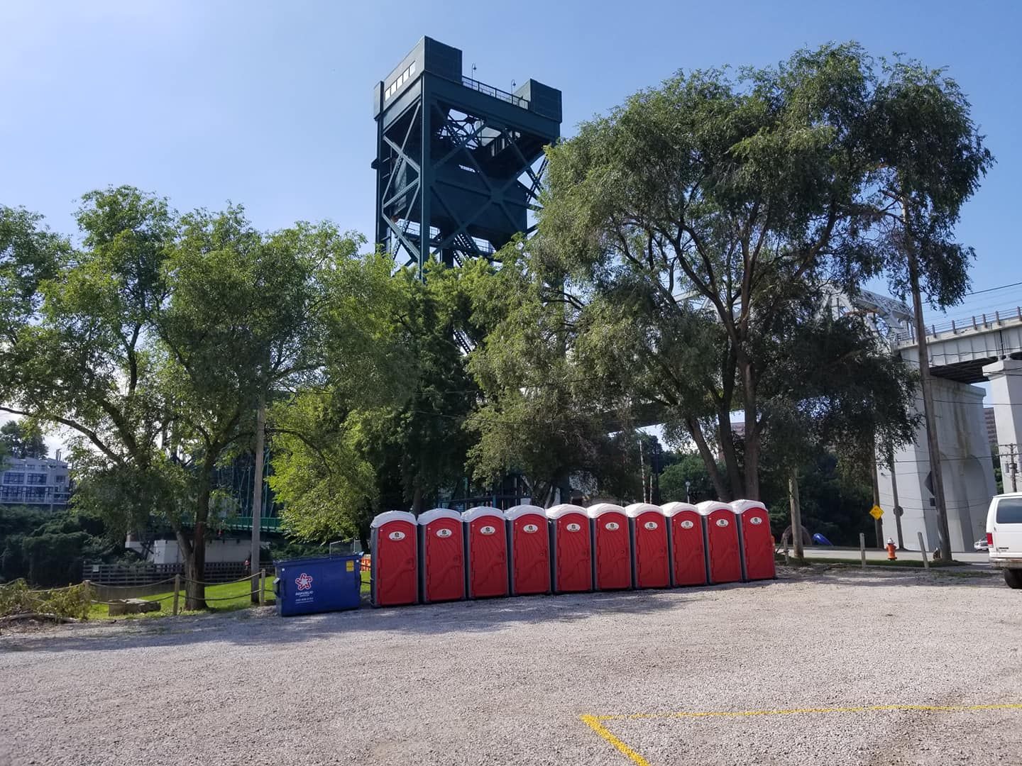 A row of red portable toilets are lined up in a parking lot.