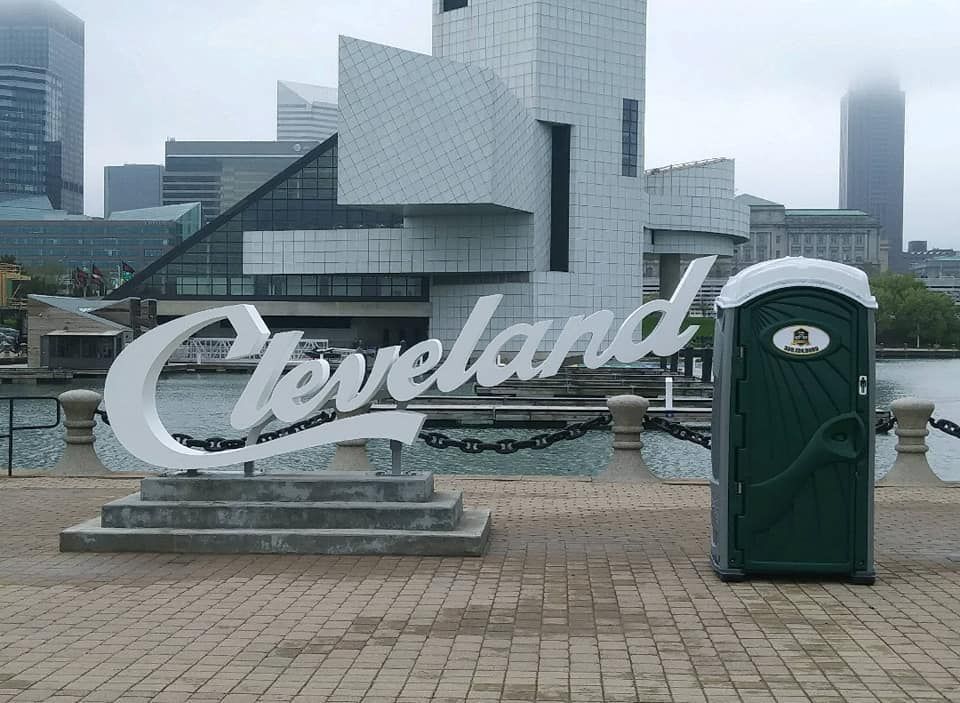 A sign that says cleveland next to a portable toilet