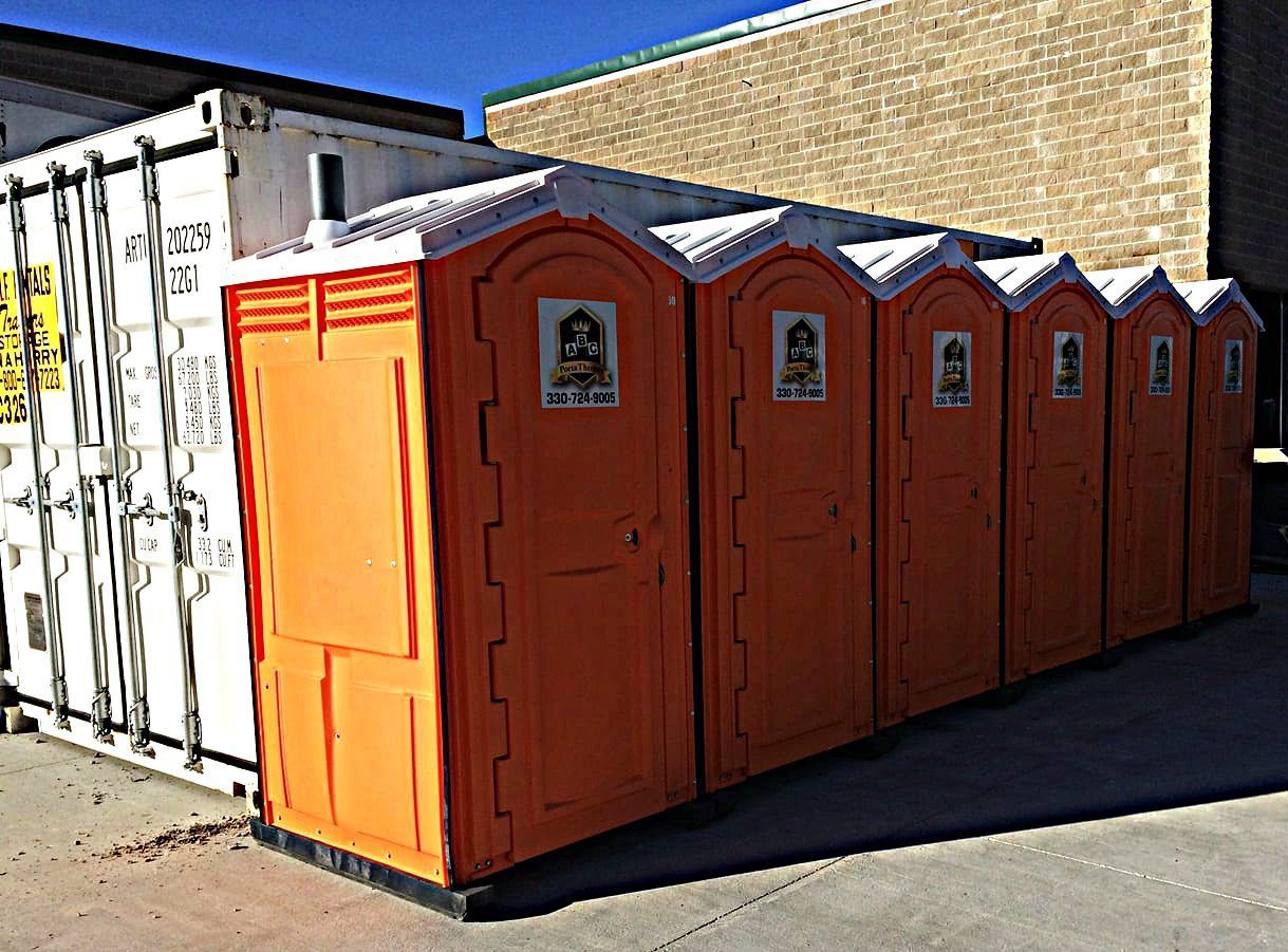 A row of orange portable toilets are lined up next to each other