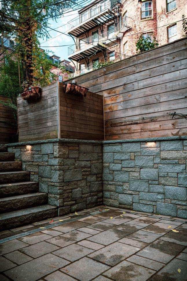 A stone wall with stairs leading up to it and a building in the background.