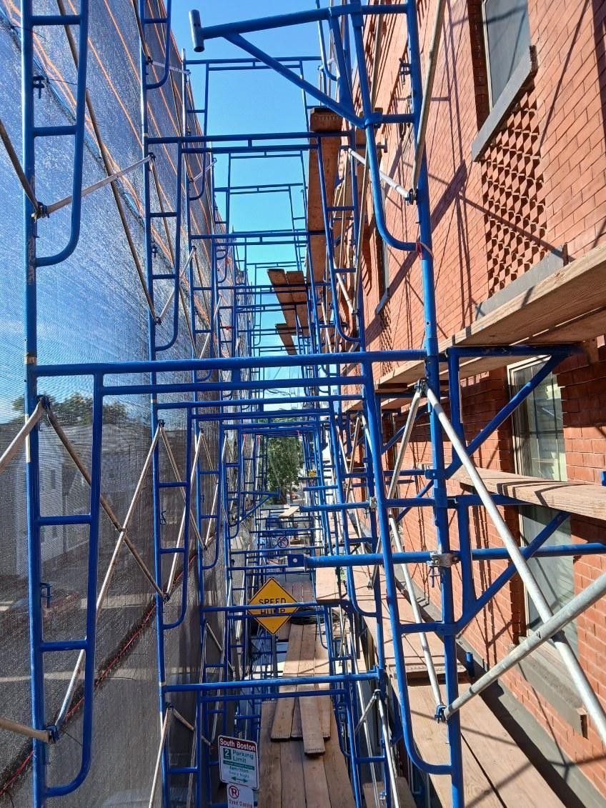 A row of blue scaffolding along the side of a building