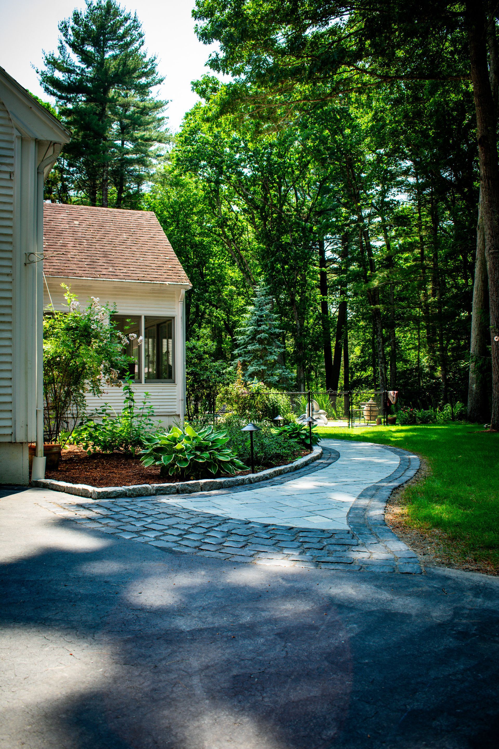 A driveway leading to a house in the woods.