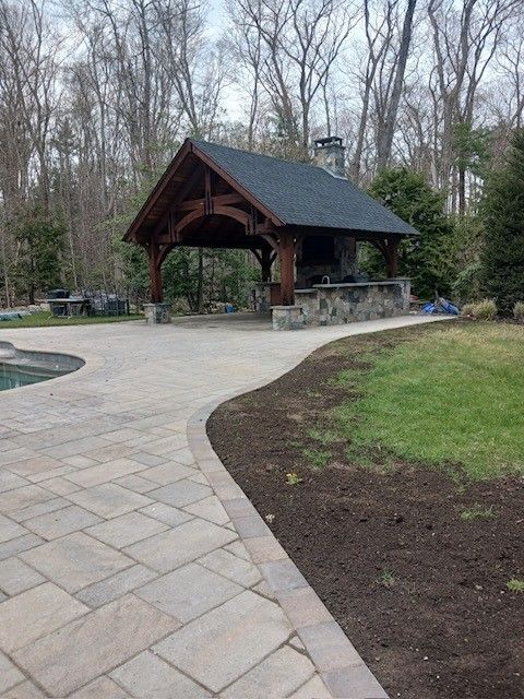 A patio with a gazebo and a swimming pool in the background.