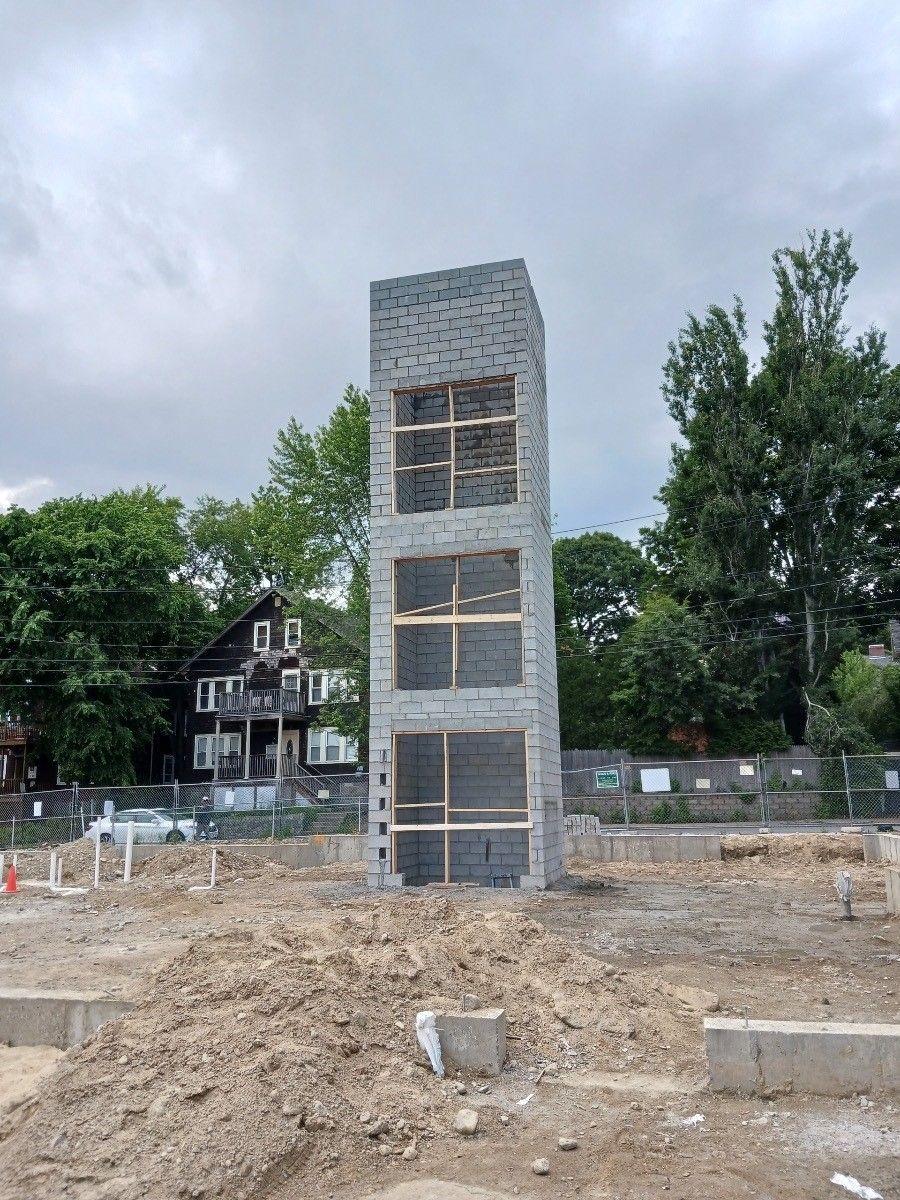 a tall brick building is being built in a dirt field