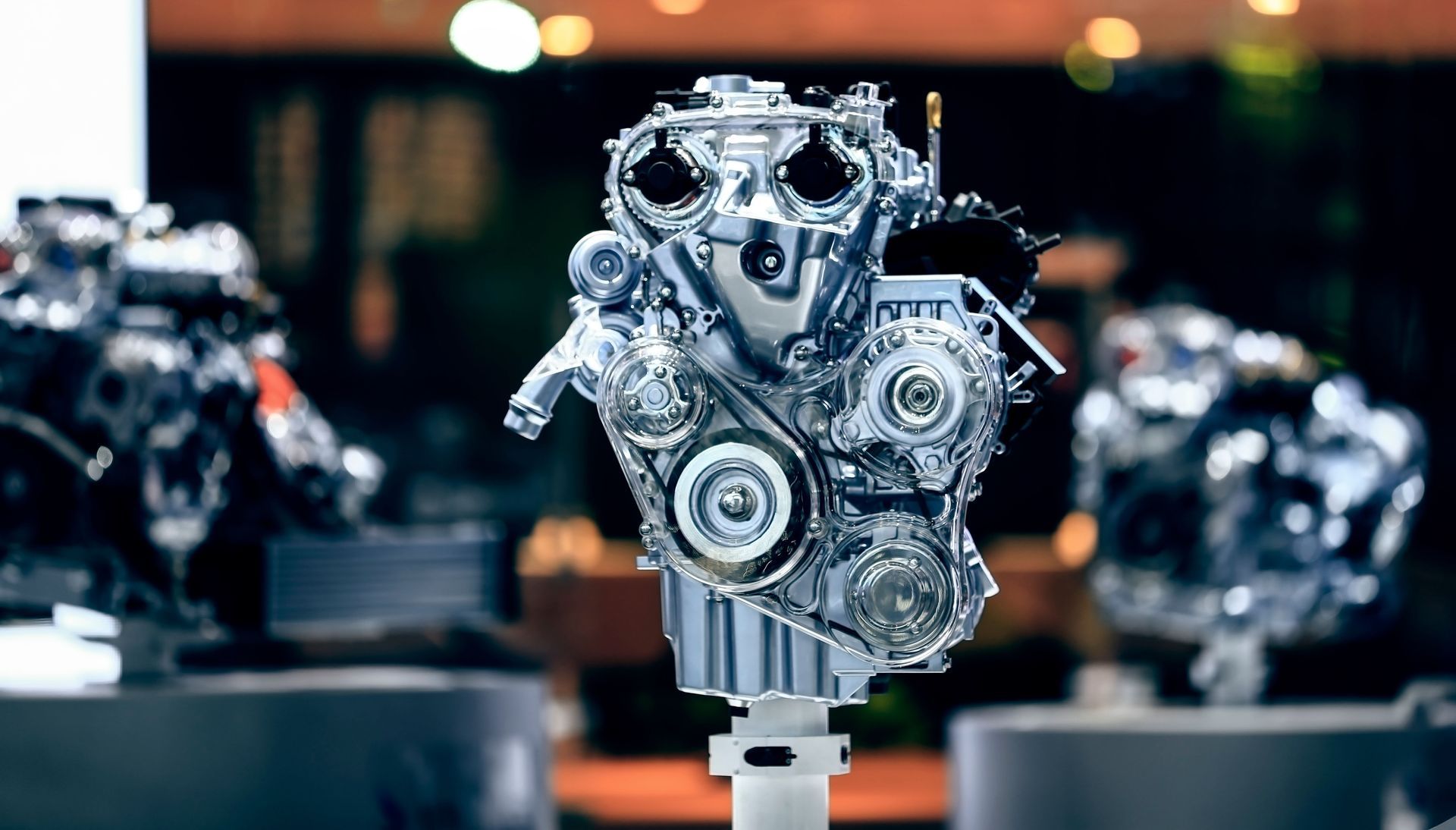 Shiny car engine on display at an auto show, surrounded by other engines.
