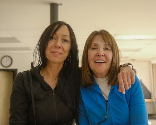 Two women are posing for a picture together and one of them has her arm around the other 's shoulder.