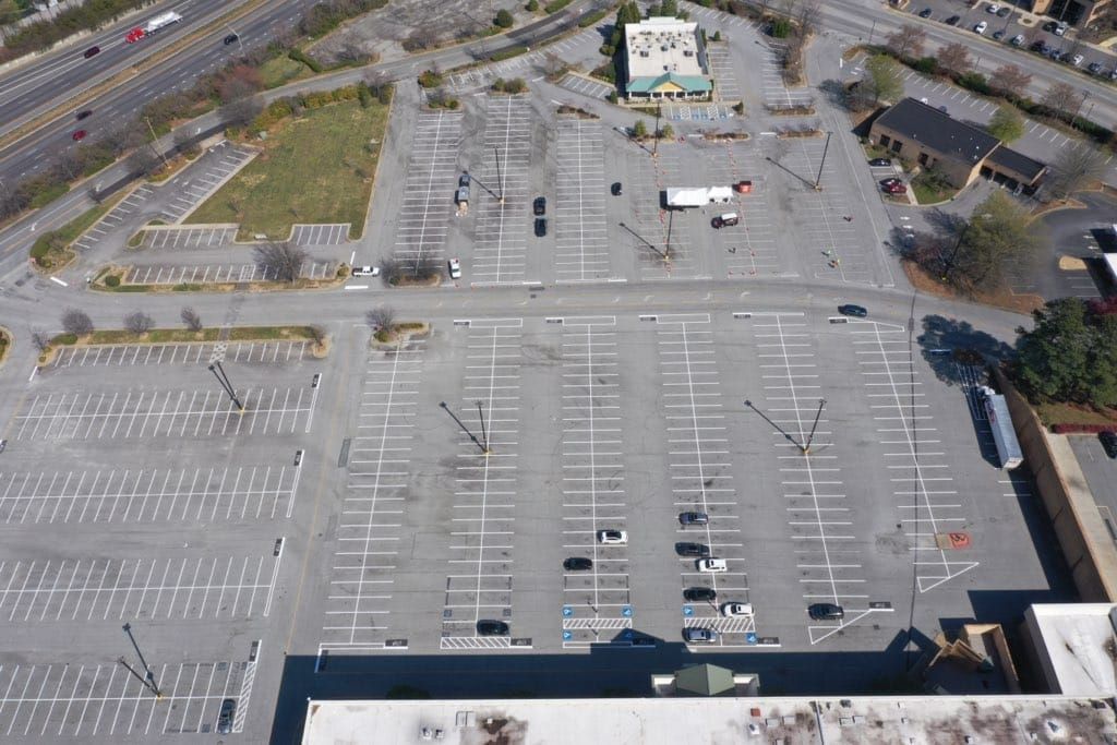 An aerial view of an empty parking lot with cars parked in it.