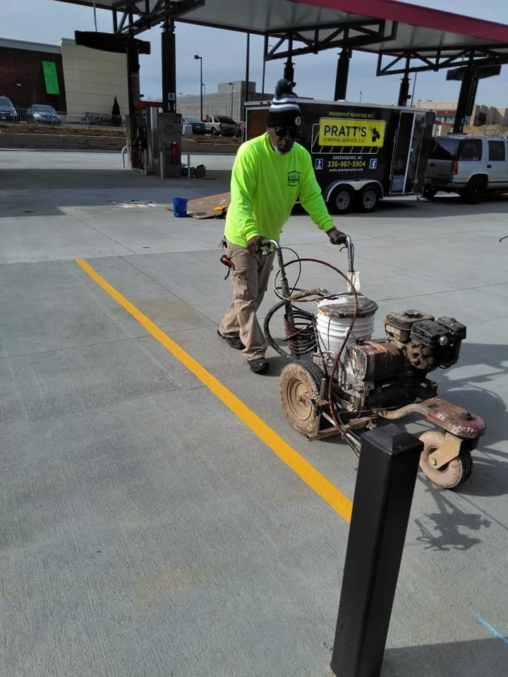 A man is painting a yellow line on a parking lot