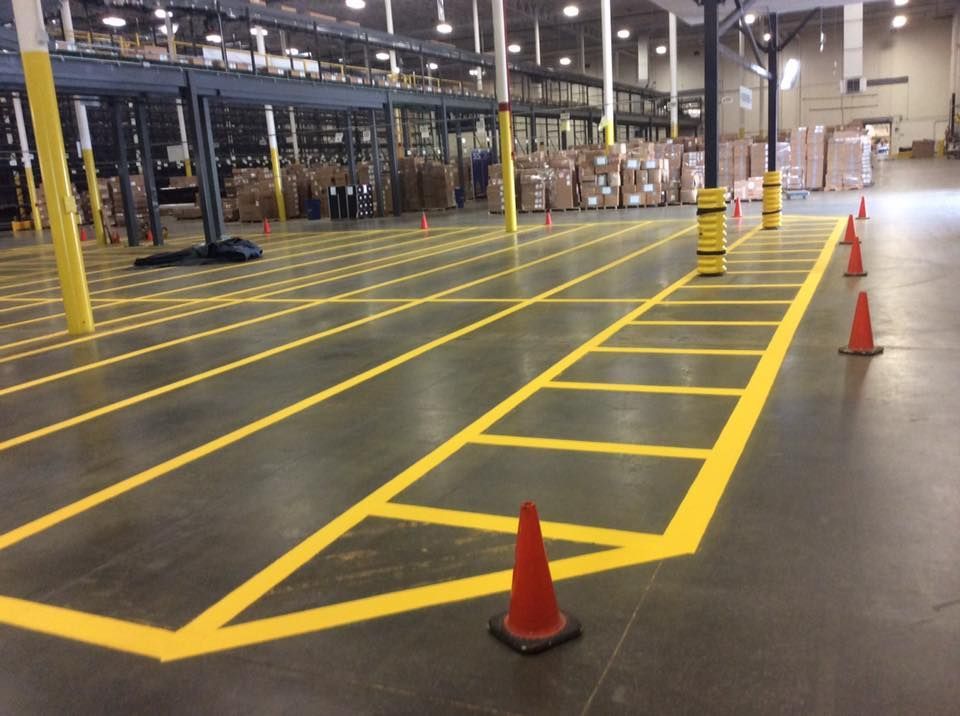 A large warehouse with yellow lines and red cones