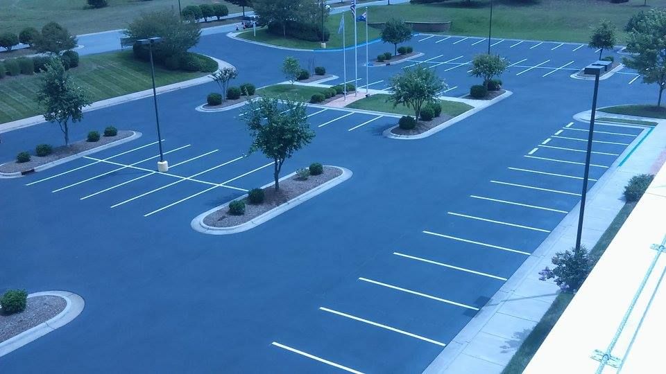 An aerial view of an empty parking lot with trees in the middle.