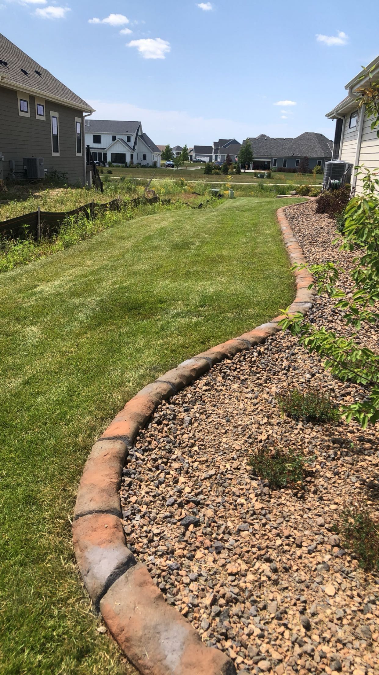 A lawn with a brick curb and a gravel path leading to a house.
