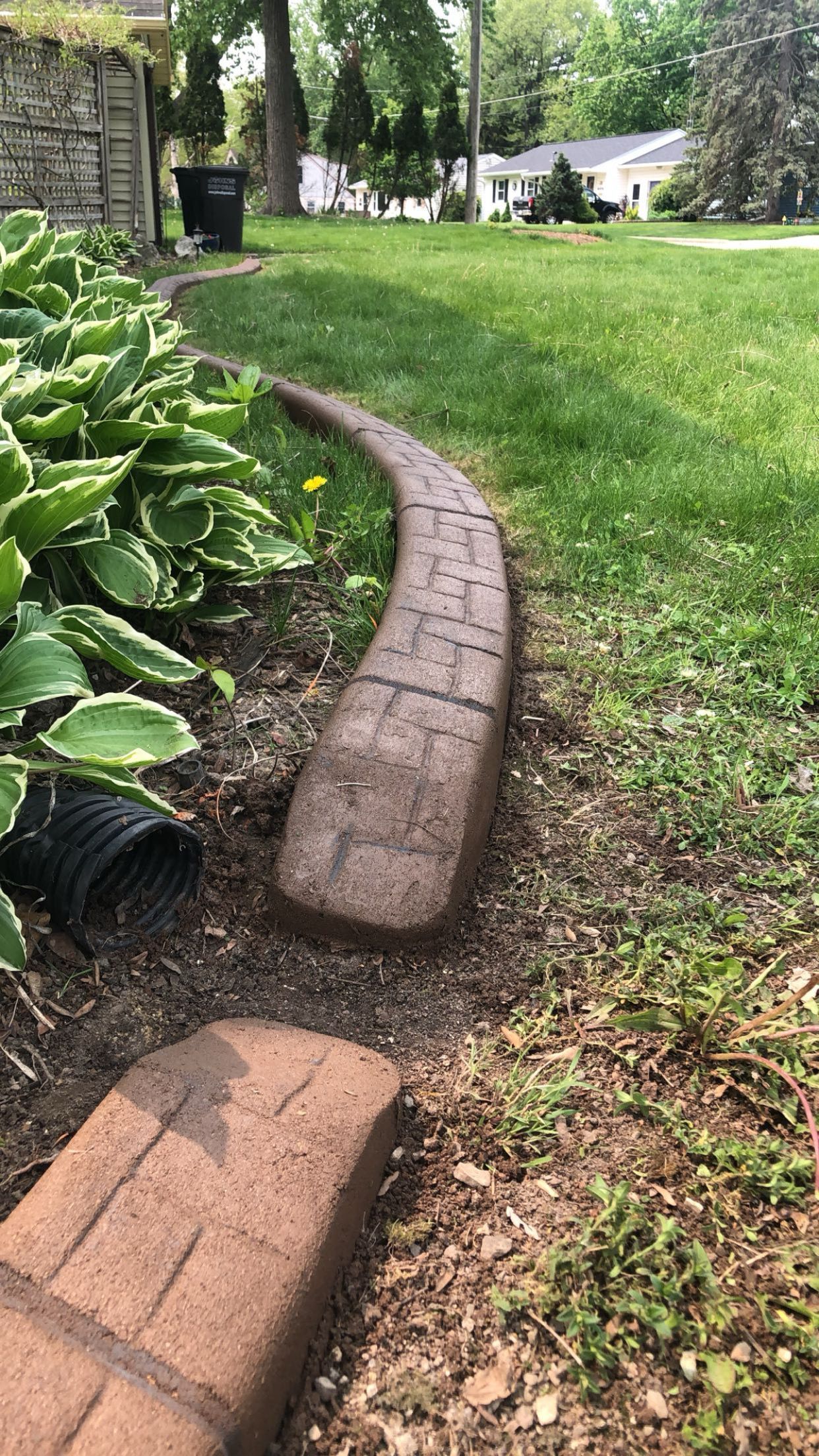 A brick walkway is going through a lush green garden.