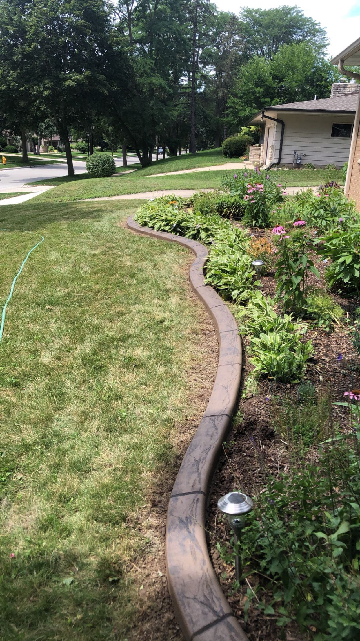 A concrete curb in a garden next to a house.