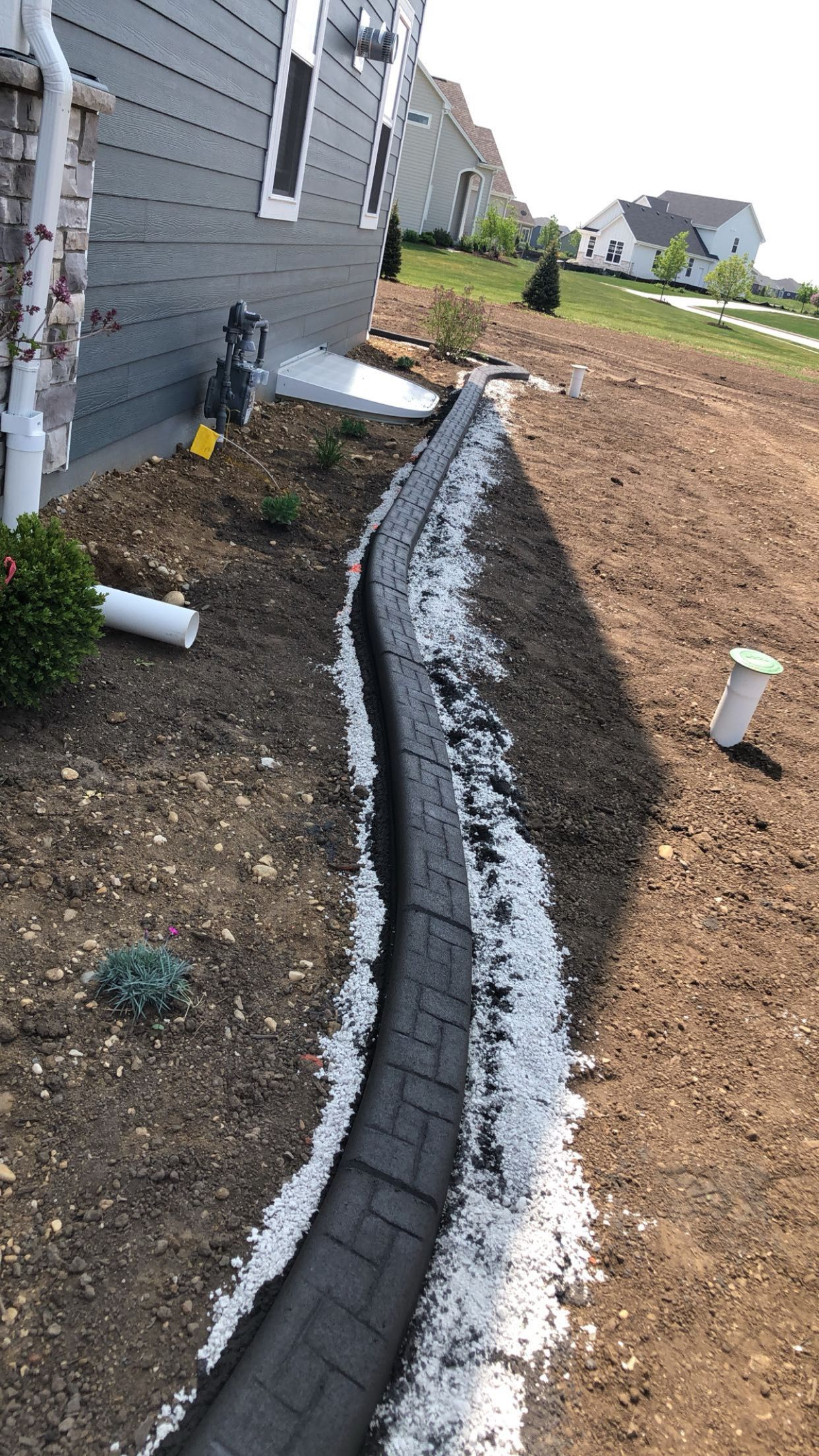A drainage system is being installed on the side of a house.