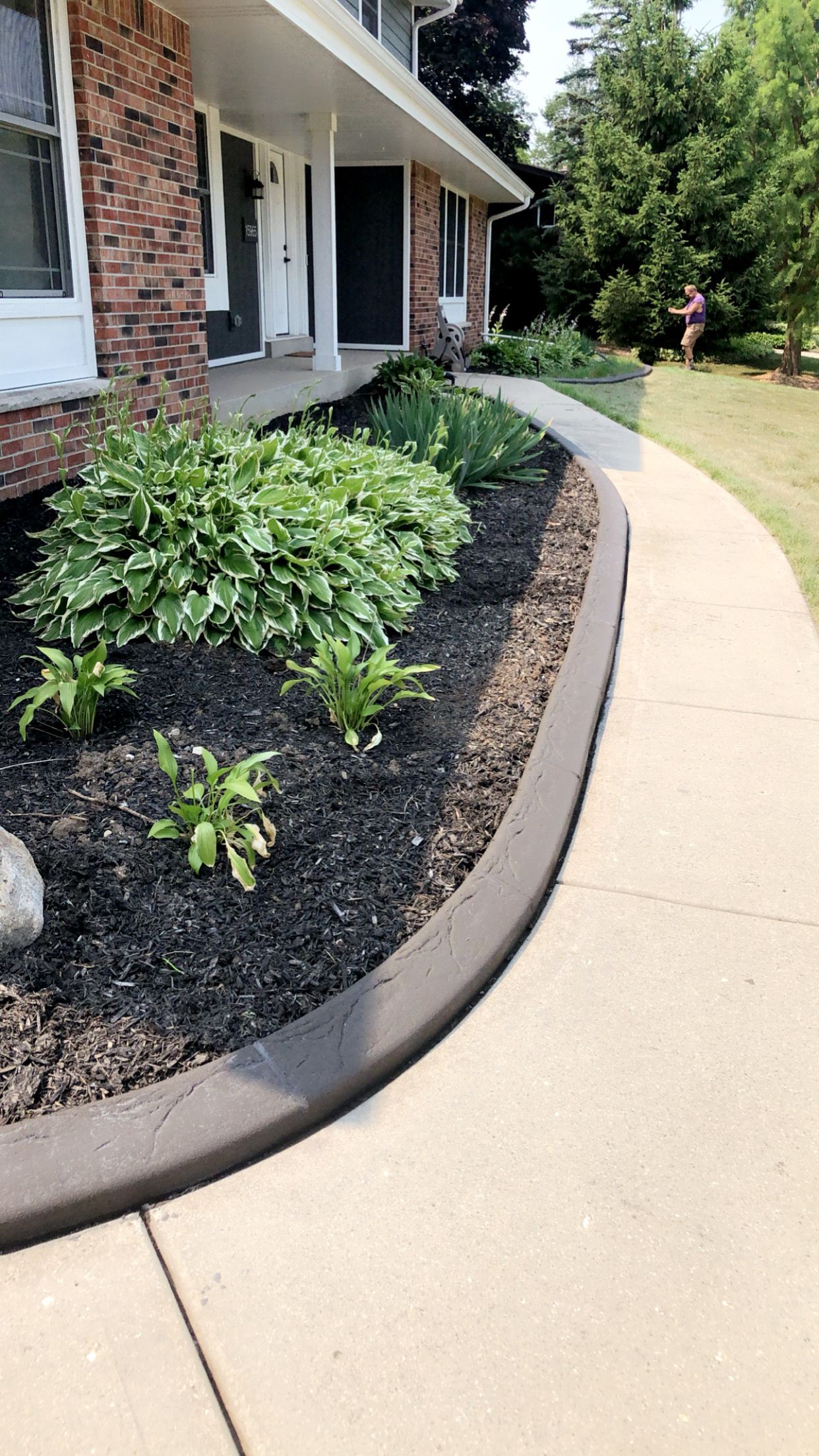 A brick house with a concrete walkway leading to it.