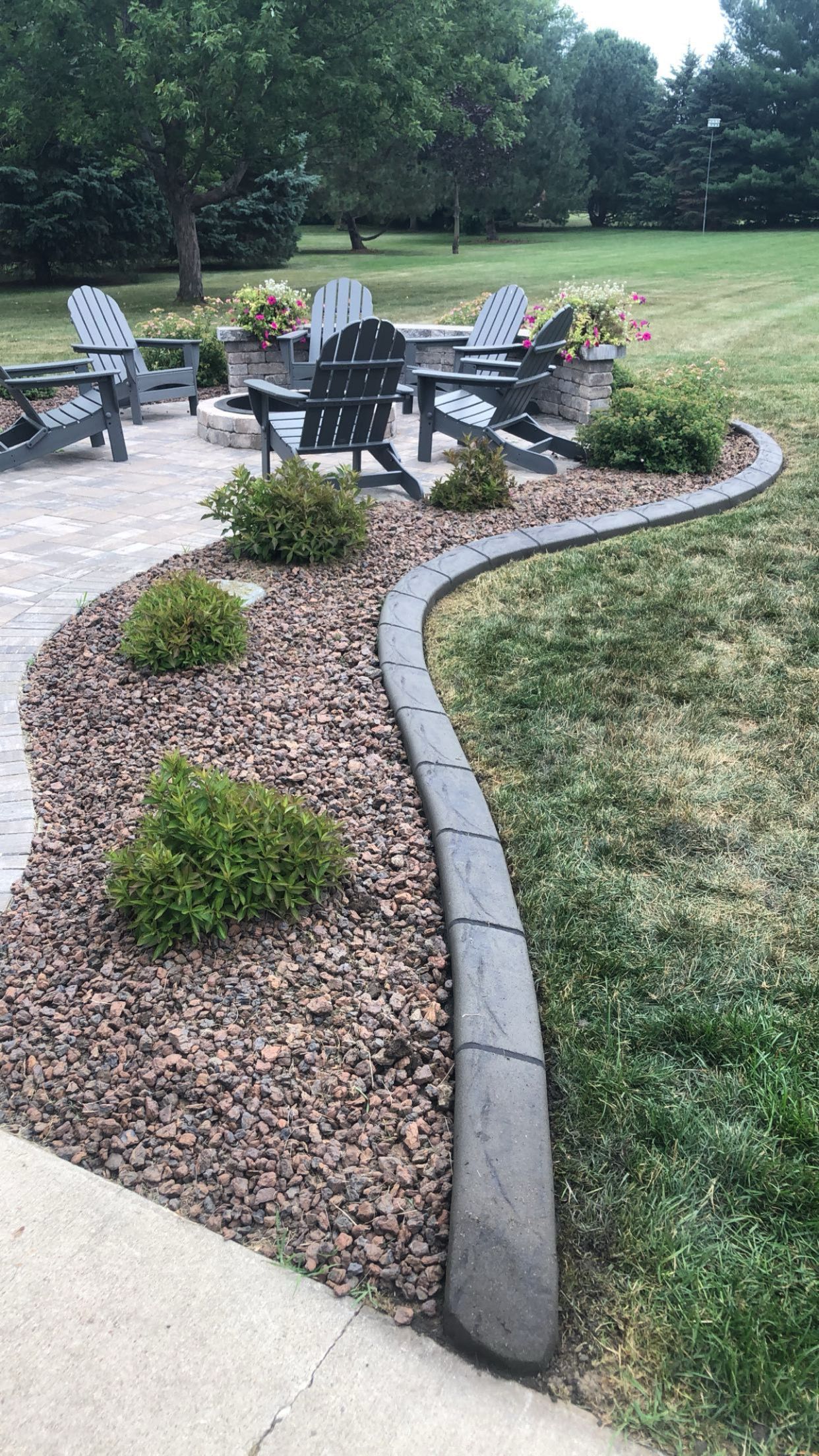 A patio with chairs and a fire pit in the backyard.