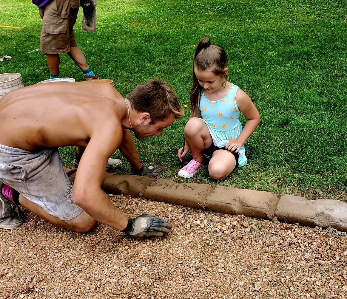 A man and a little girl are playing in the dirt