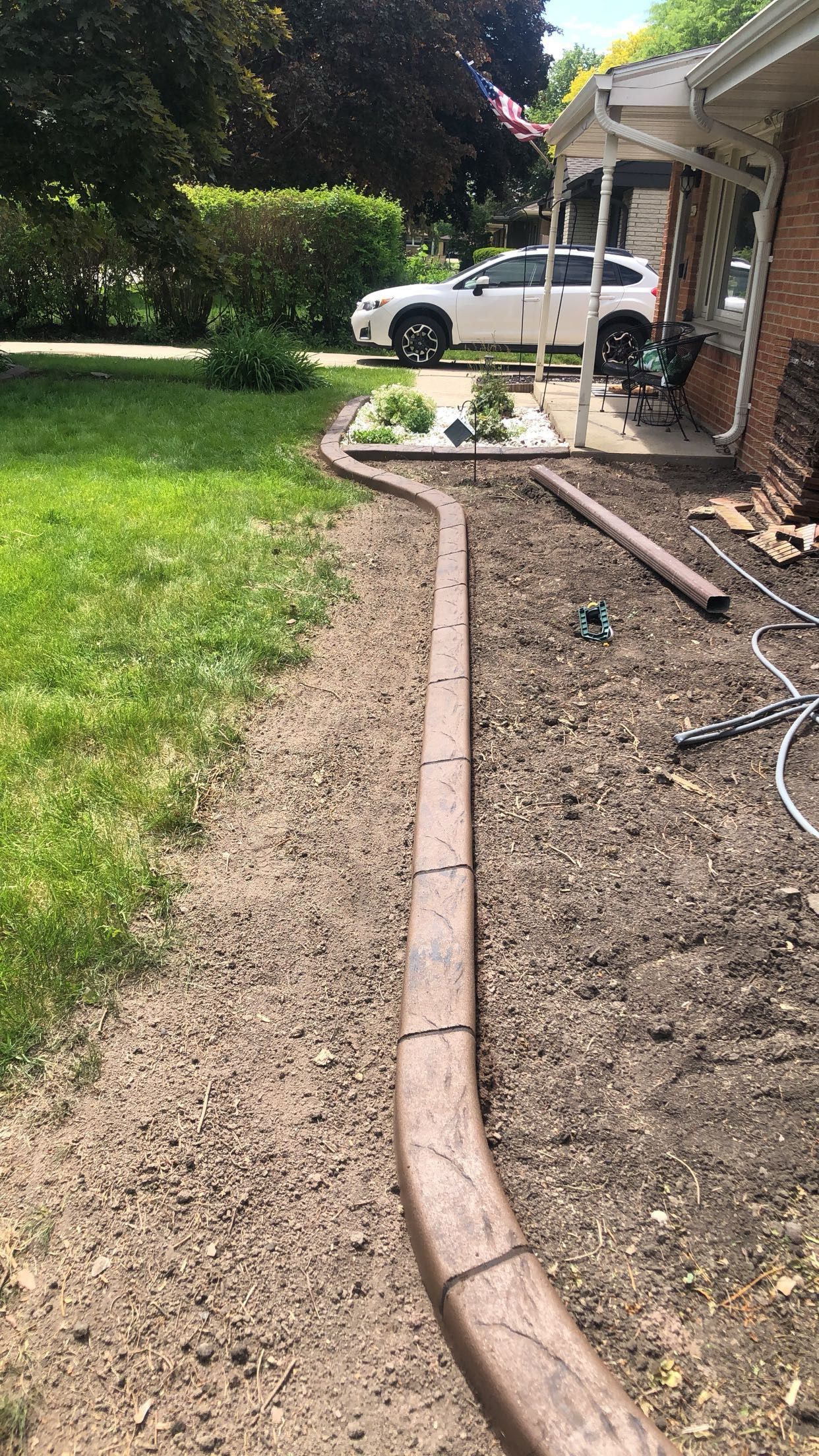 A concrete curb is being installed in front of a house.