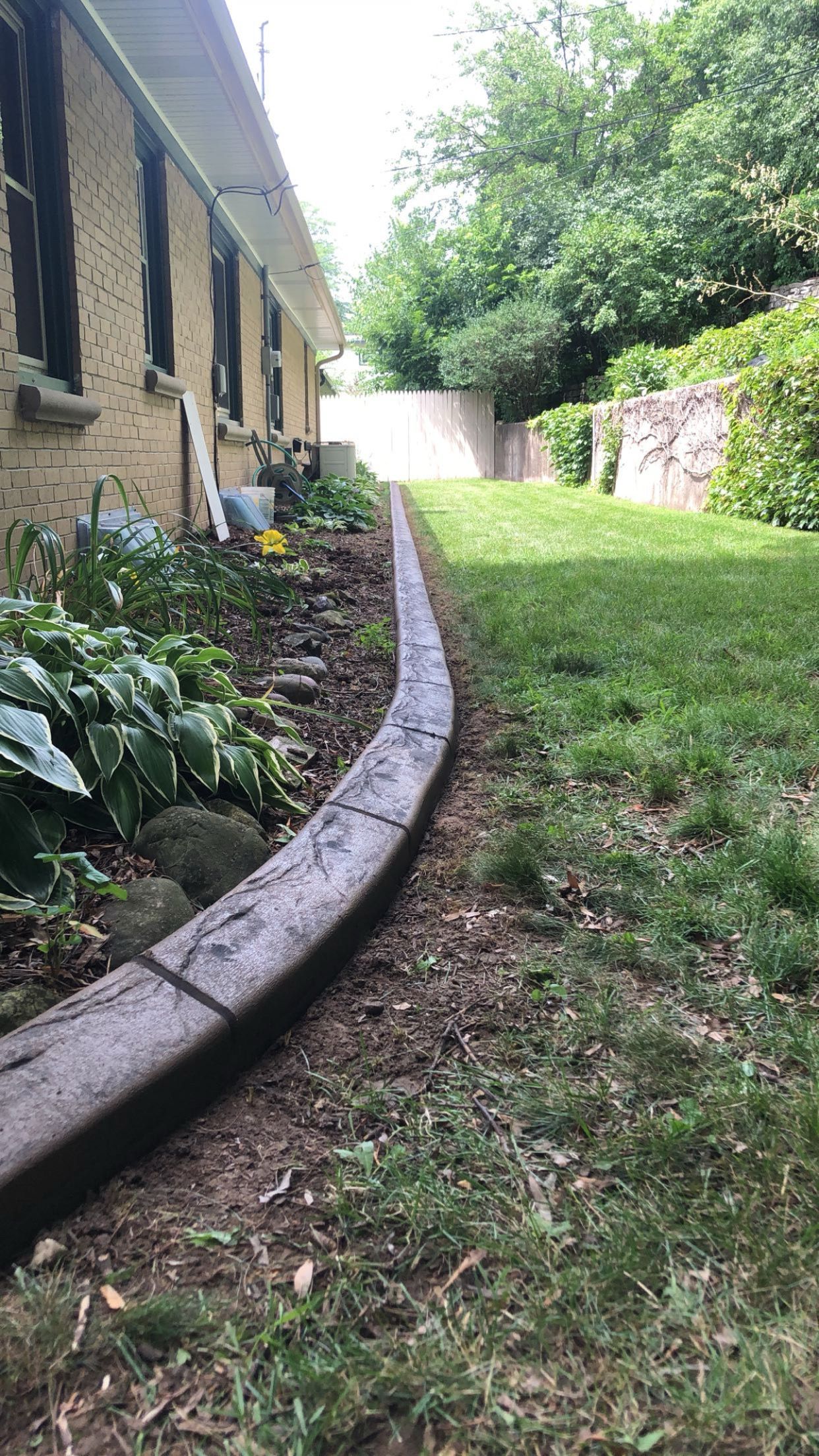 A concrete curb is being installed in front of a house.