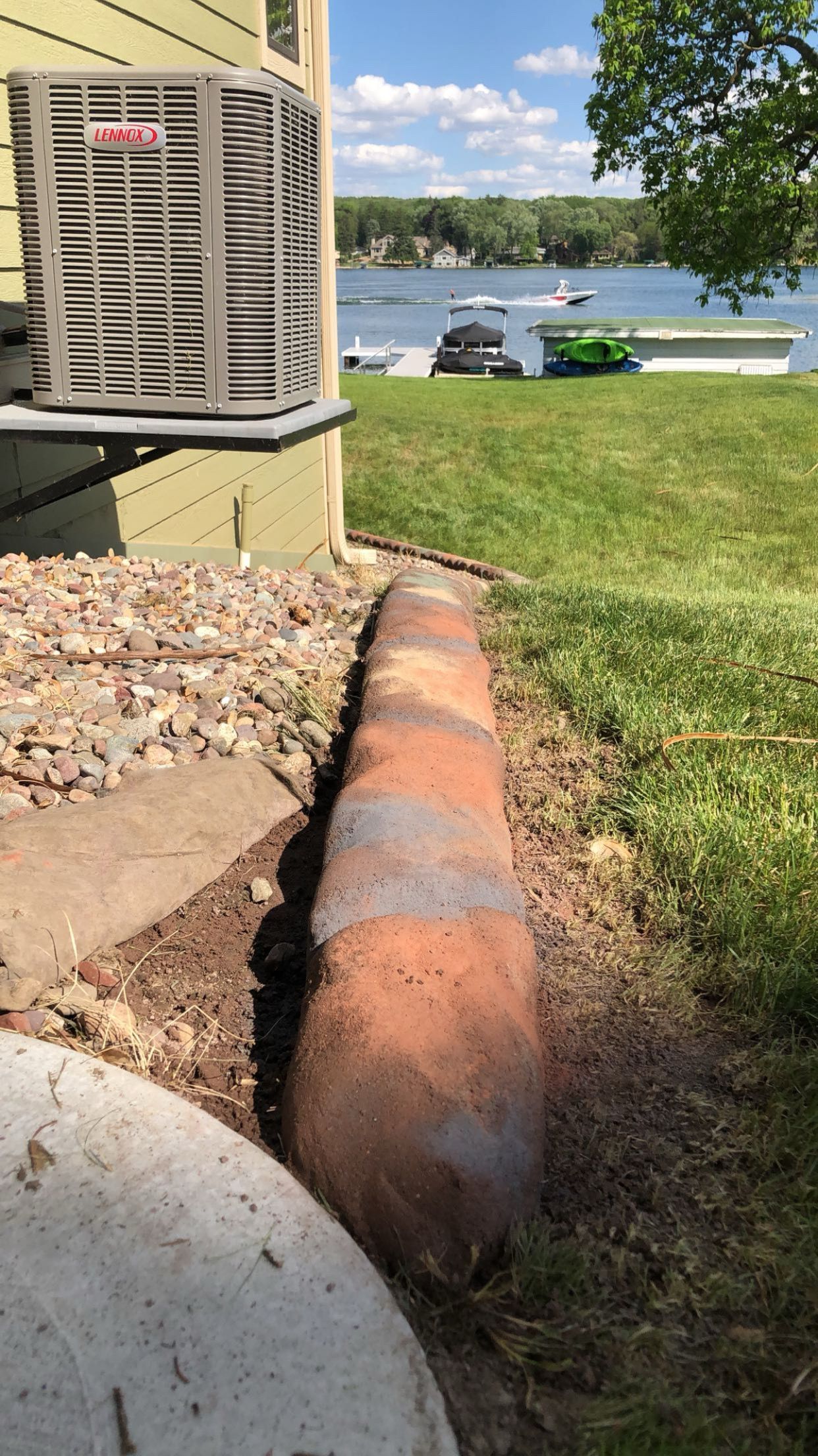 A large piece of wood is sitting in the grass next to a house.