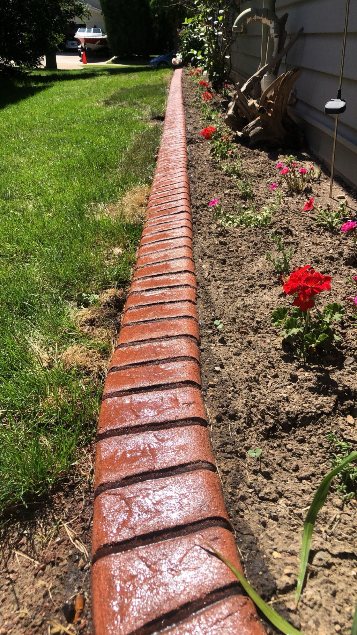 A long brick walkway going through a garden next to a house.