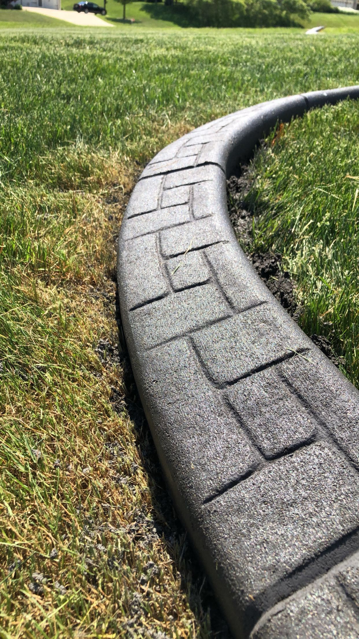 A concrete curb is sitting in the middle of a lush green field.