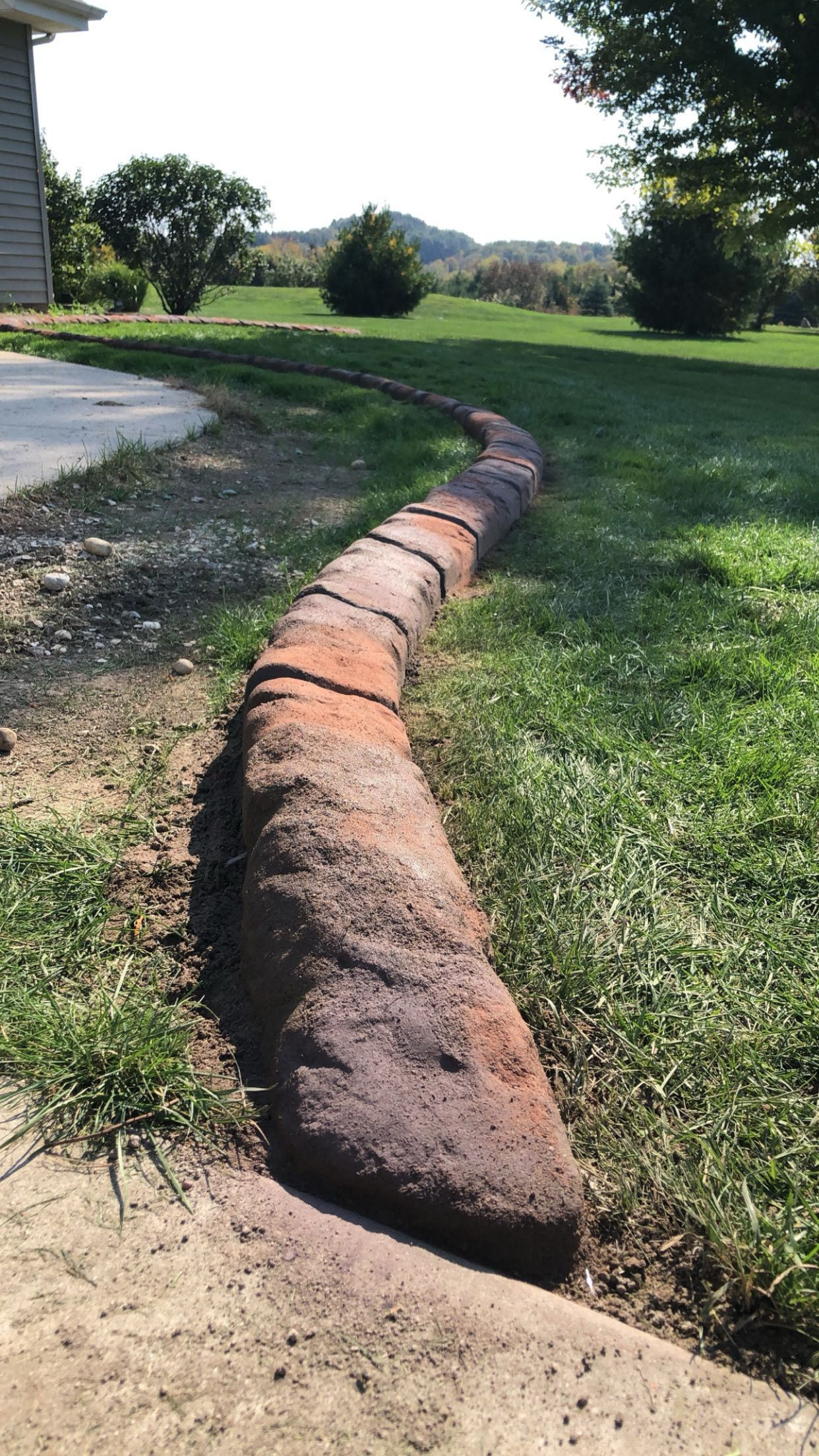 A brick walkway is being built in the grass next to a house.