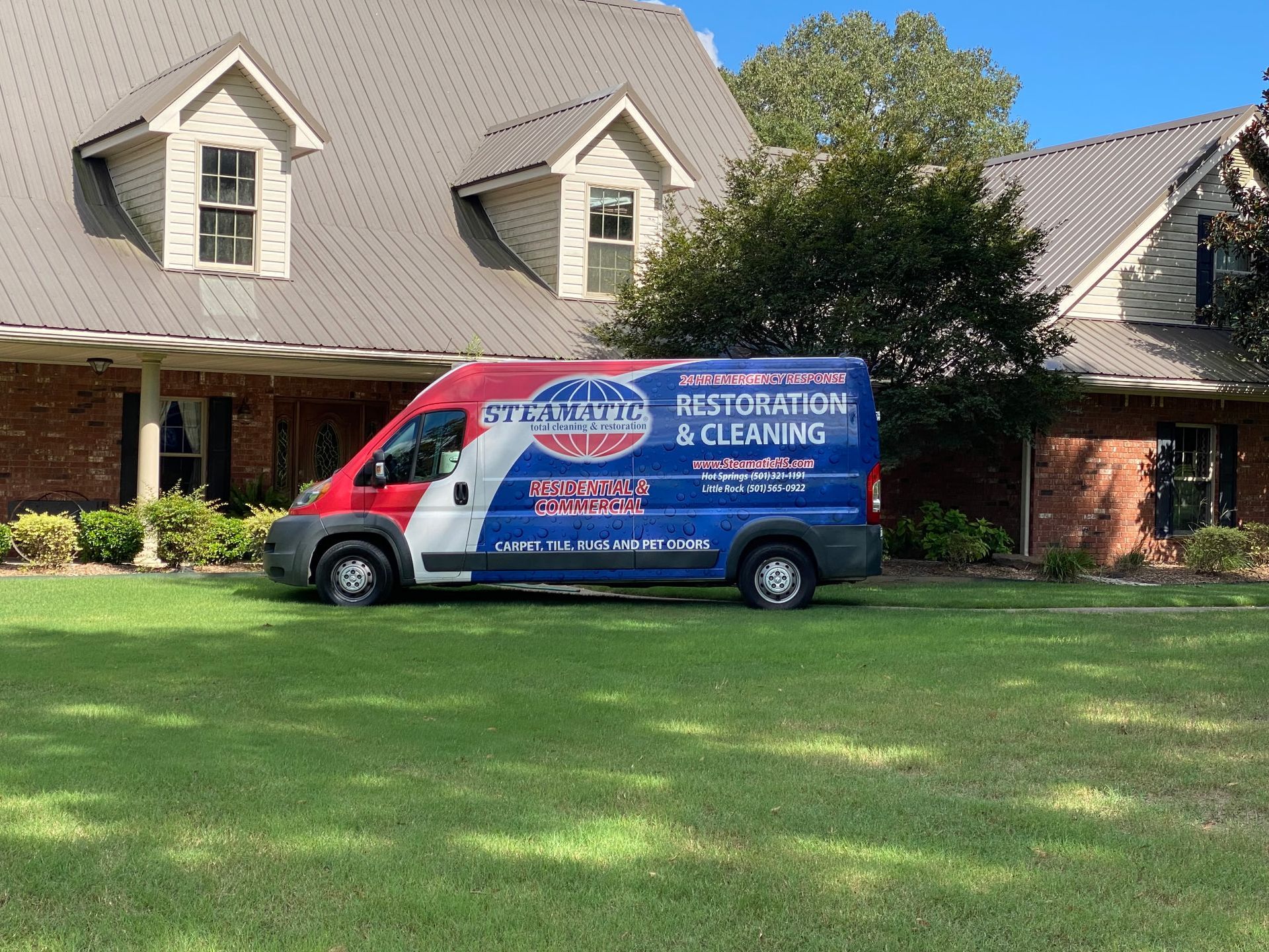 Red, white, and blue van parked in front of a building with snow on the ground. An Arkansas flag flies in the background.
