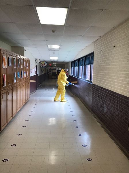A person in a yellow suit is cleaning a hallway