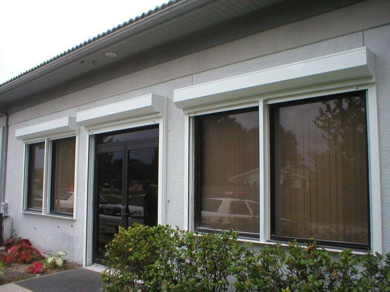 Exterior of a white house with large windows, a glass door, and shrubs in front