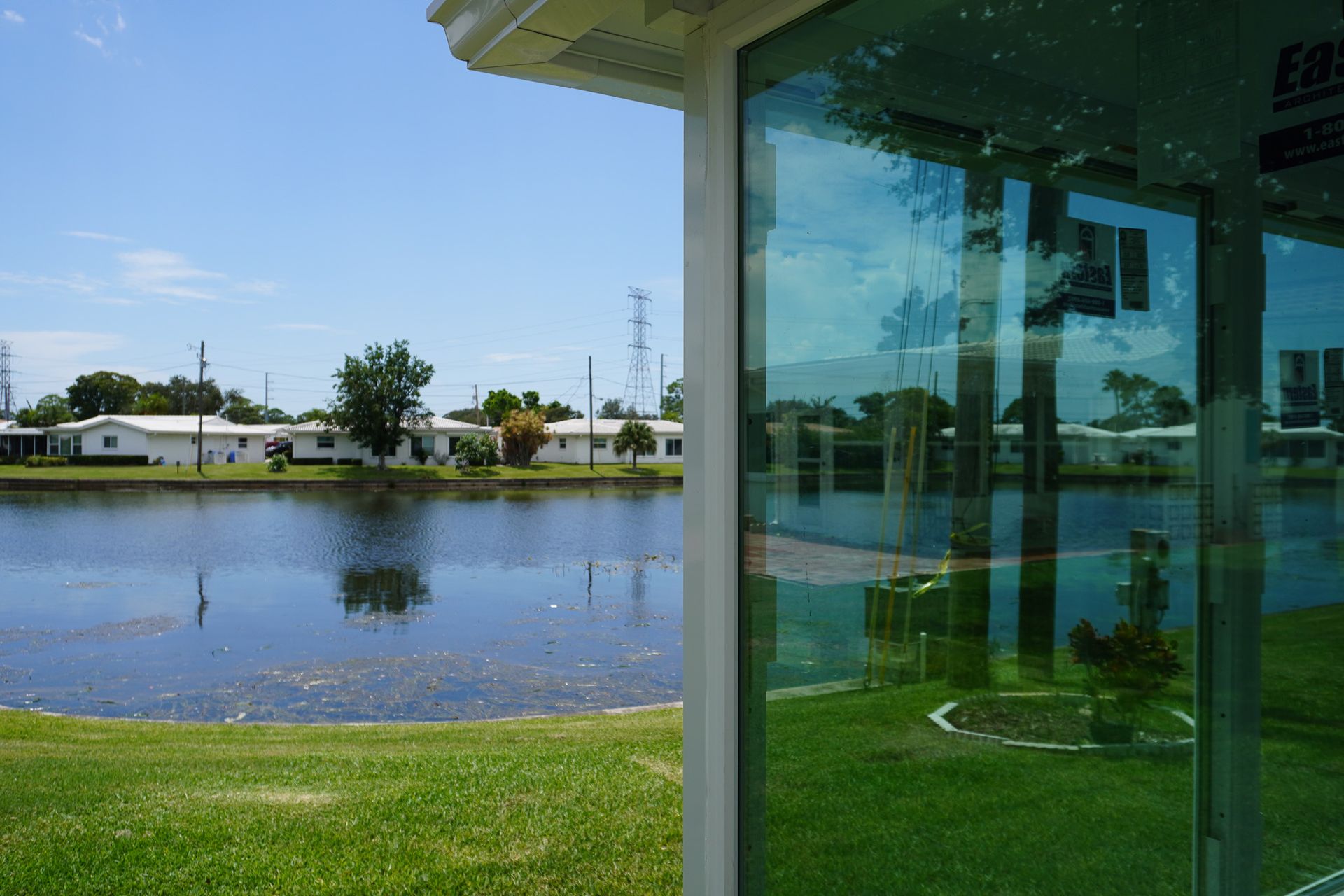 View from a glass porch over a pond and grassy shore on a sunny day