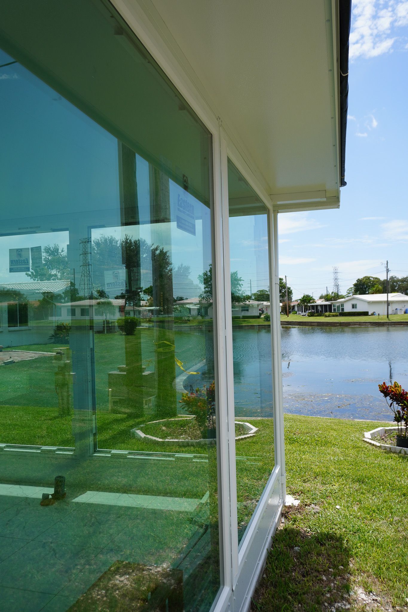 Sliding glass doors beside a green yard and pond under a bright blue sky