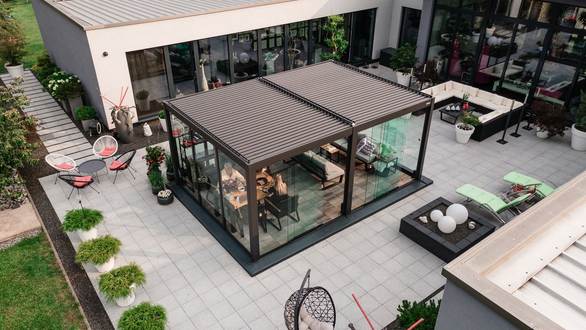 Courtyard patio with a glass gazebo, lounge chairs, potted plants, and outdoor seating surrounding it