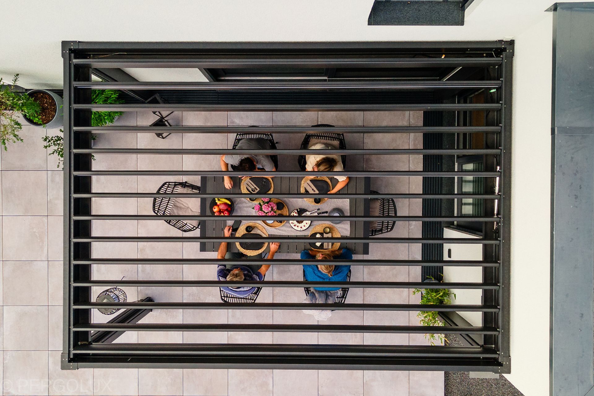 Overhead view of six people sitting around a table in a courtyard behind a metal railing